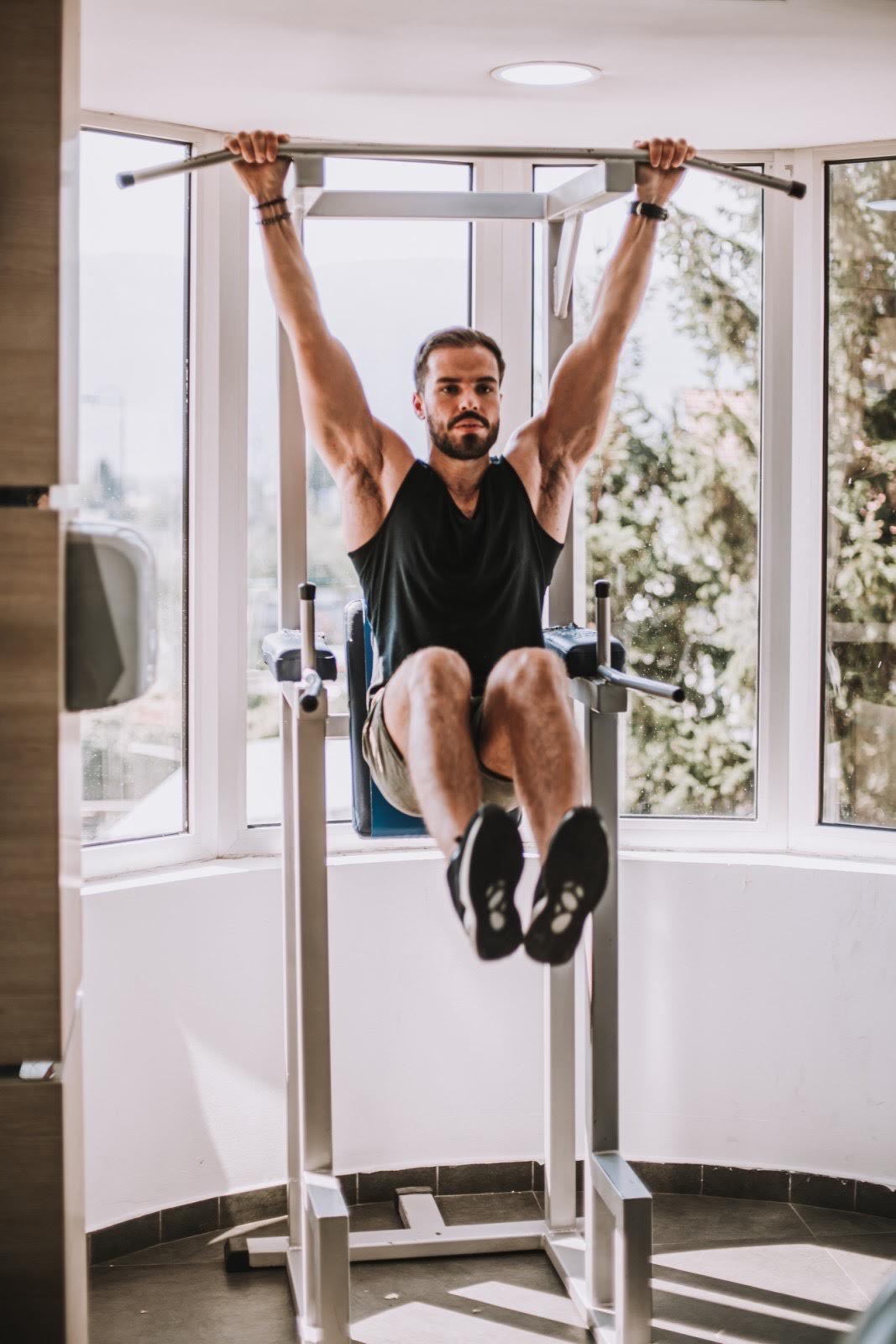 Trainer demonstrating hanging leg raise exercise for core strength